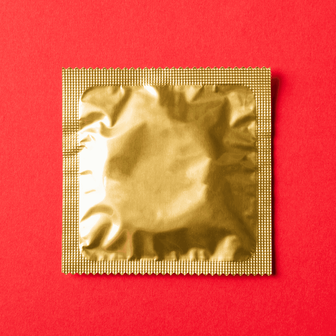 Gold metallic wrapped condom with a red background